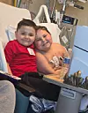 Two children sitting closely together on a hospital bed in a medical room.
